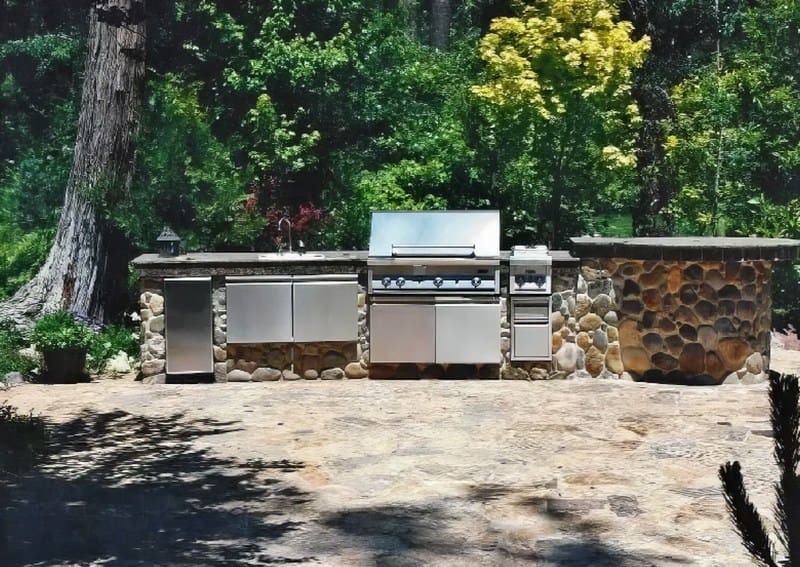 A grill and an outdoor kitchen in the middle of a yard.